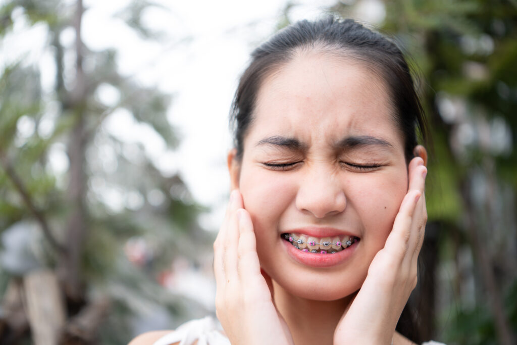 Portrait of a young asian woman with pain from braces on her teeth